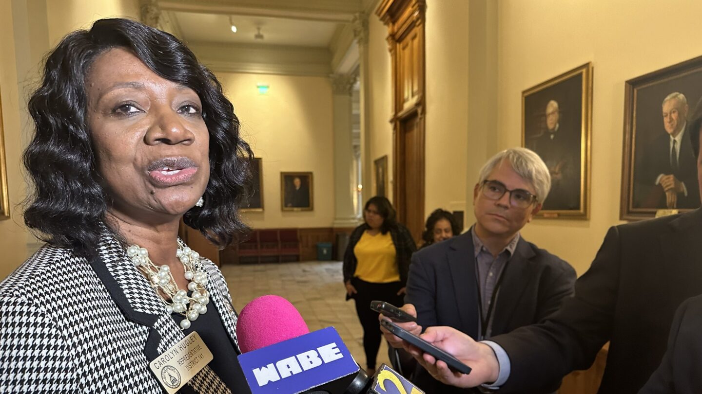 Georgia State House Minority Leader Carolyn Hugley talks to a crowd of reporters holding microphones