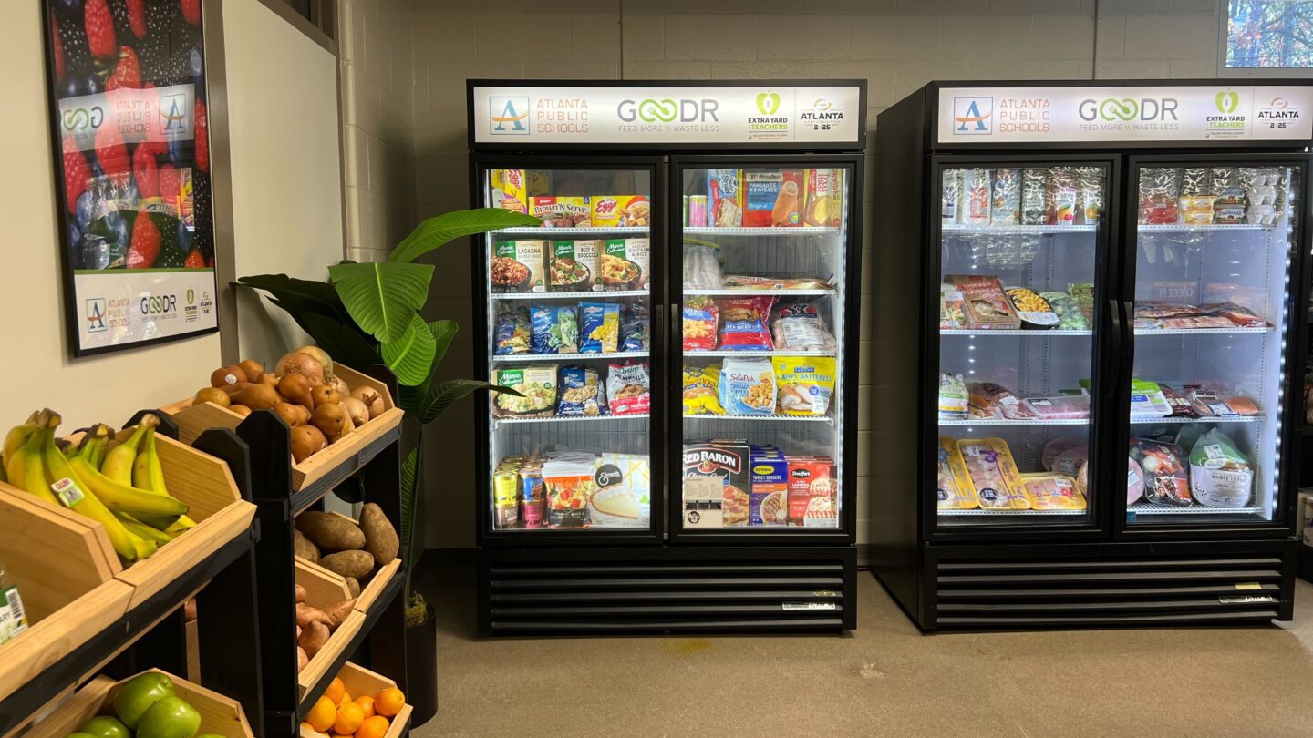 A grocery store with two freezers and a rack of produce.