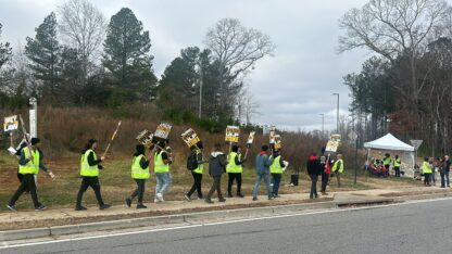 Dozens of drivers wave signs outside the DGT8 delivery station in Alpharetta, Georgia, in a strike launched by the Teamsters union.