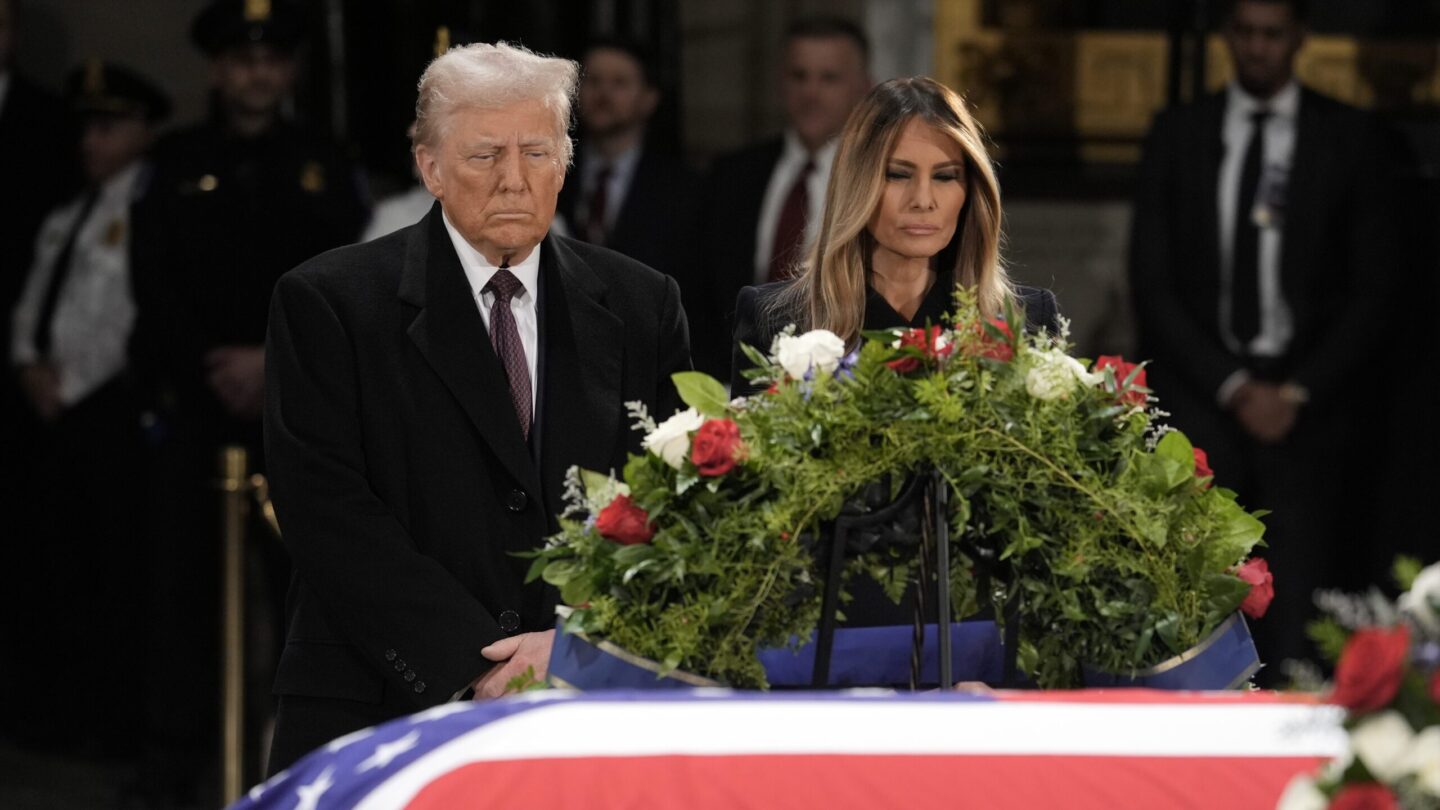 Donald and Melania Trump stand in front of the flag-draped casket of former President Jimmy Carter.