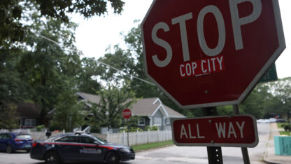 A police car drives through an intersection near Brownwood Park where a stop sign has been modified in opposition to the Atlanta Public Safety Training Center that protesters refer to as Copy City.